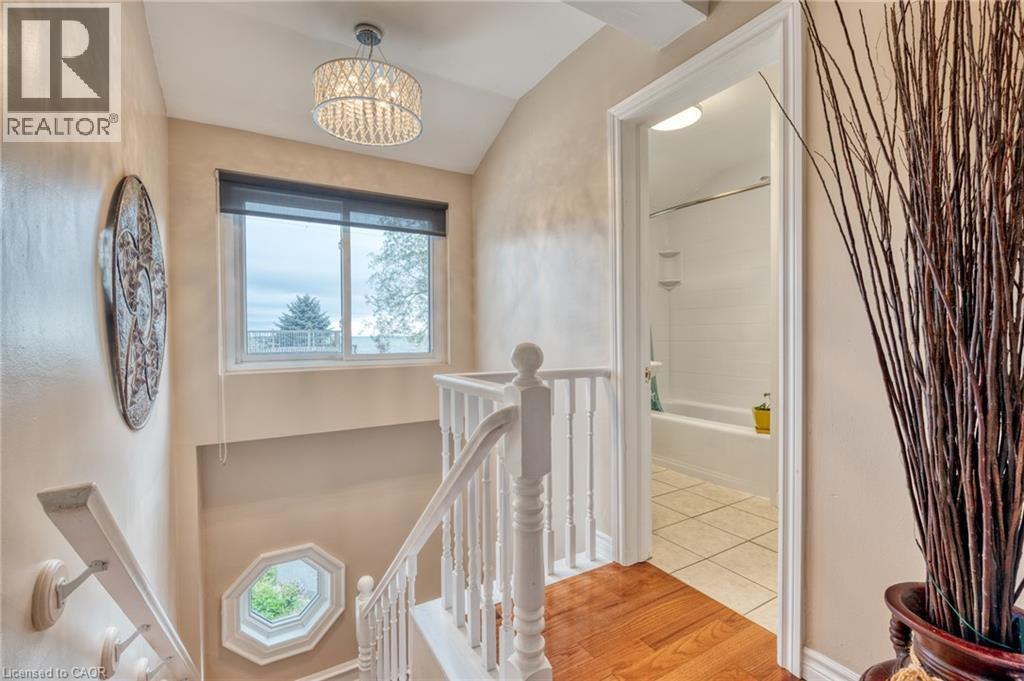 Hardwood flooring in the upper-level hallway, featuring a crystal chandelier and a window with a roller shade - 851 Beach Boulevard, Hamilton, ON - Indoor Photo Showing Other Room