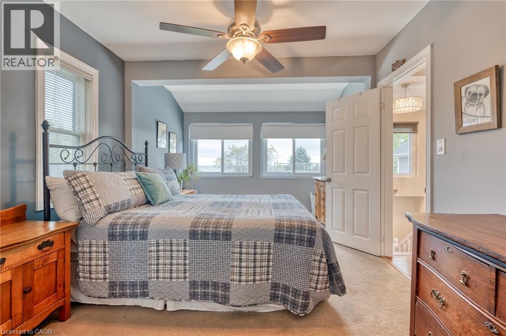 Comfortable bedroom featuring a ceiling fan with light fixture, multiple windows with blinds, a paneled door, and carpet flooring - 851 Beach Boulevard, Hamilton, ON - Indoor Photo Showing Bedroom