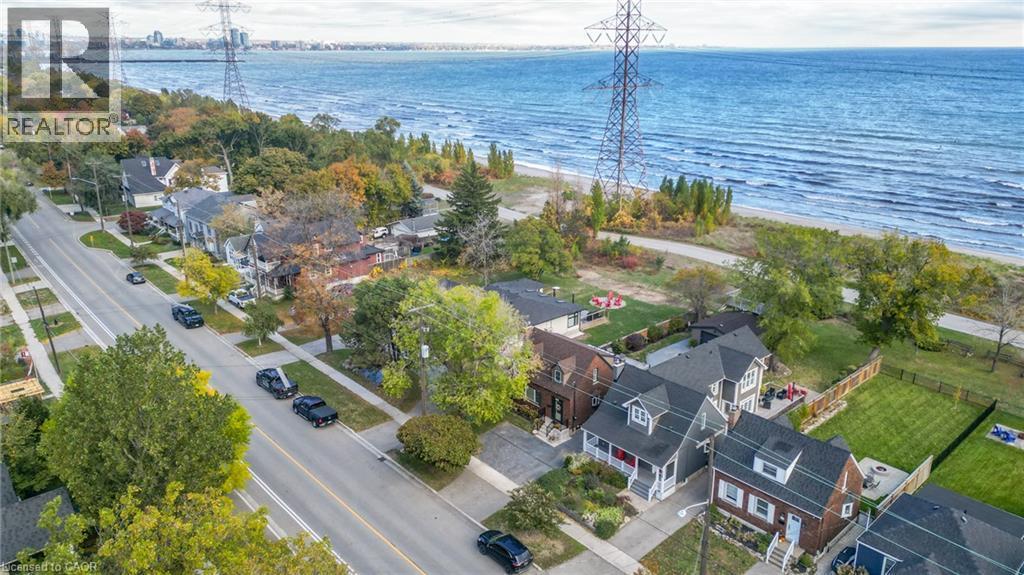Aerial perspective of a street lined with residential properties, featuring a prominent waterfront with a distant city skyline - 851 Beach Boulevard, Hamilton, ON - Outdoor With Body Of Water With View