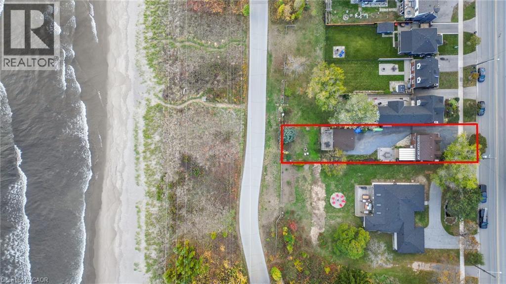 Aerial perspective highlighting the property outlined in red, positioned between a paved roadway and a sandy beach with ocean waves - 851 Beach Boulevard, Hamilton, ON -