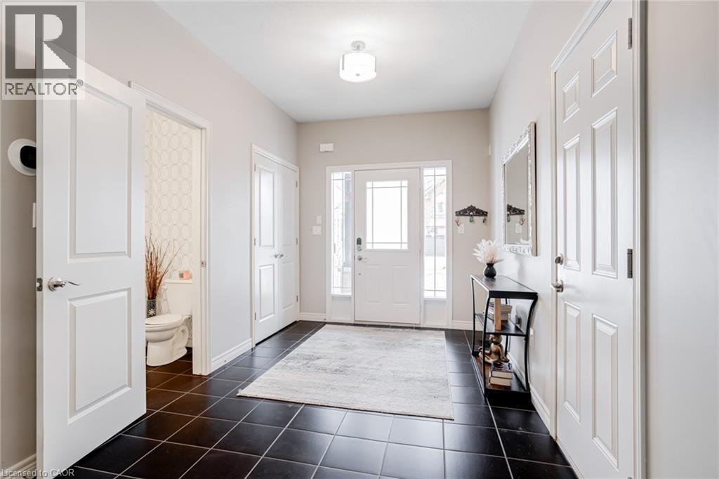 Entry foyer featuring dark square floor tiles, a white front door with decorative glass inserts, and an overhead flush-mount light fixture - 7 Kinsman Drive, Binbrook, ON - Indoor Photo Showing Other Room