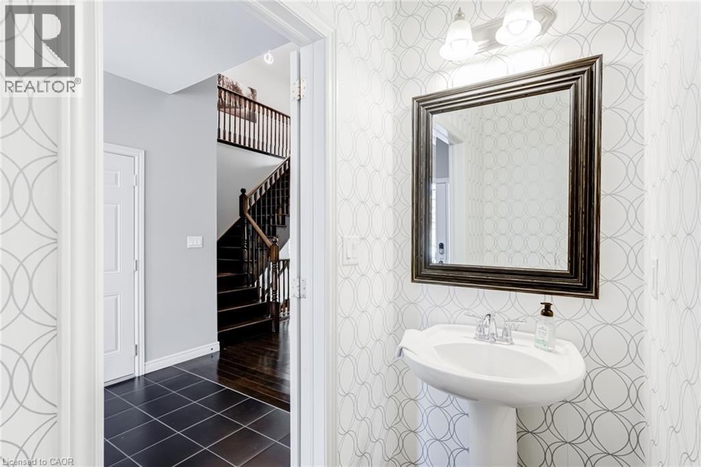Pedestal sink with chrome faucet, framed mirror, and two-light vanity fixture - 7 Kinsman Drive, Binbrook, ON - Indoor Photo Showing Bathroom