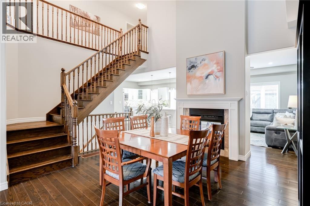 Two-story foyer featuring wood-finish flooring and a grand staircase with turned wood balusters - 7 Kinsman Drive, Binbrook, ON - Indoor Photo Showing Dining Room With Fireplace