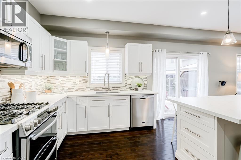 Kitchen featuring white shaker-style cabinetry, stainless steel appliances, mosaic tile backsplash, and dark wood-finish flooring - 7 Kinsman Drive, Binbrook, ON - Indoor Photo Showing Kitchen With Upgraded Kitchen