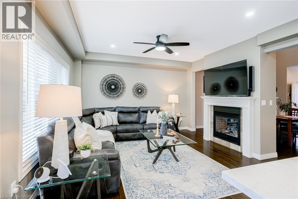 Spacious living area featuring dark wood-finish flooring and a white fireplace with a tiled surround - 7 Kinsman Drive, Binbrook, ON - Indoor Photo Showing Living Room With Fireplace