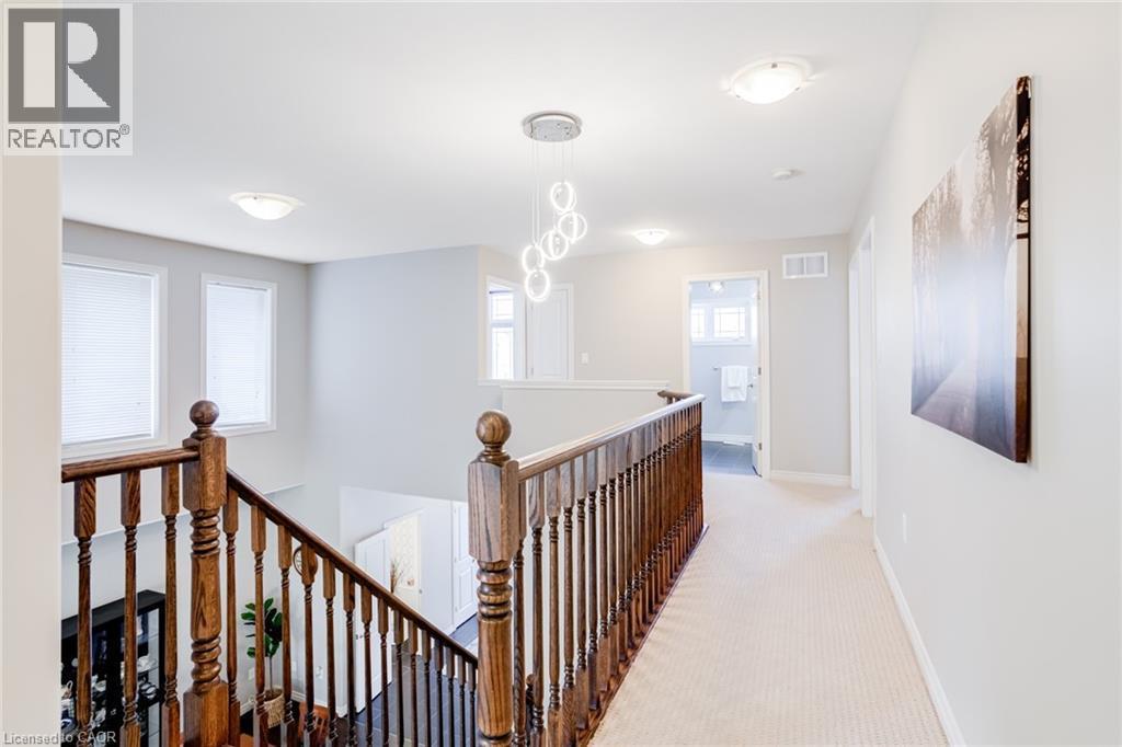 Bright hallway featuring a modern chandelier, flush-mount lighting, and light-toned carpeting - 7 Kinsman Drive, Binbrook, ON - Indoor Photo Showing Other Room