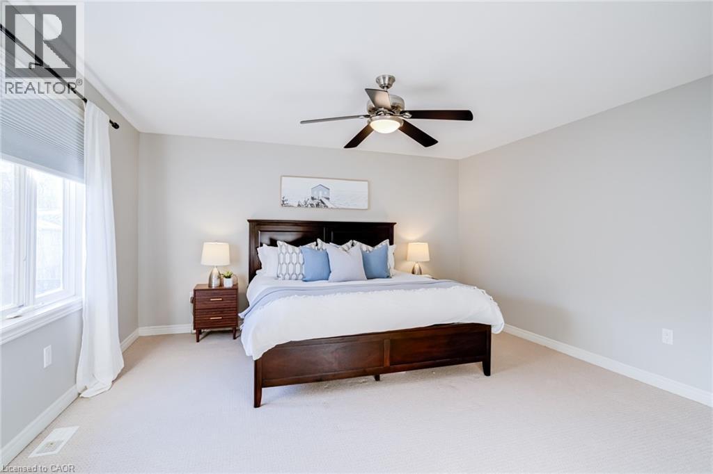 Spacious bedroom featuring light-colored carpet flooring, a large window with blinds and sheer curtains, and a ceiling fan with integrated lighting - 7 Kinsman Drive, Binbrook, ON - Indoor Photo Showing Bedroom