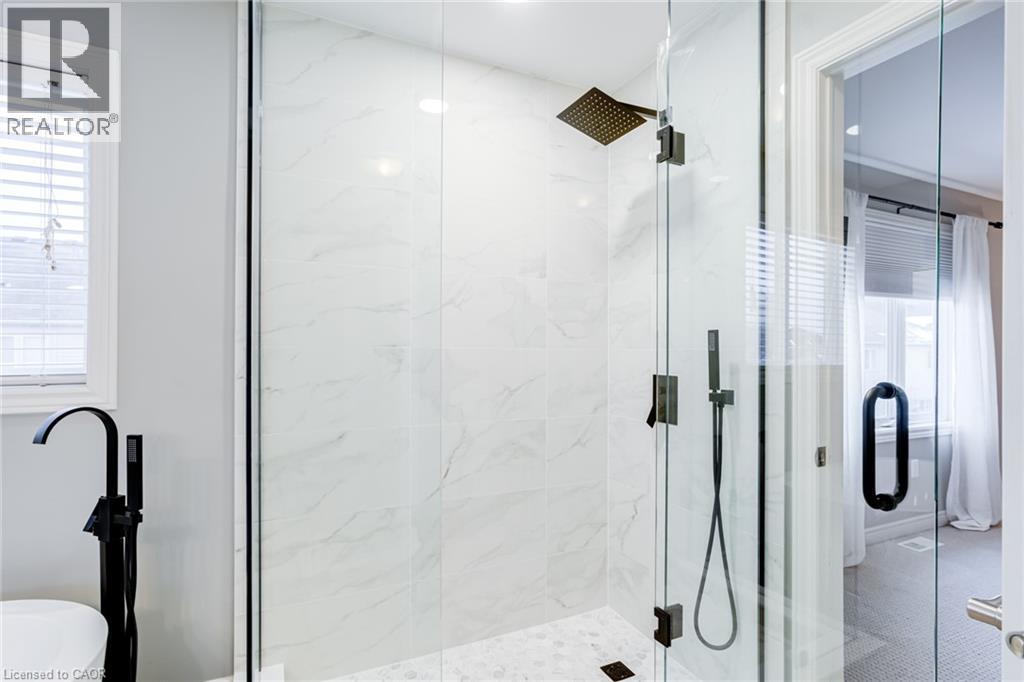 Glass-enclosed shower featuring large format white tile walls, a rain shower head, and an additional handheld shower fixture - 7 Kinsman Drive, Binbrook, ON - Indoor Photo Showing Bathroom