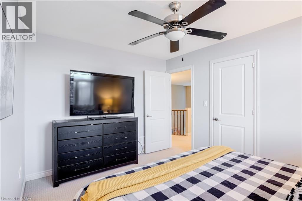 Light gray walls with white trim, a ceiling fan with brushed nickel finish and dark blades, and a textured carpeted floor - 7 Kinsman Drive, Binbrook, ON - Indoor Photo Showing Bedroom
