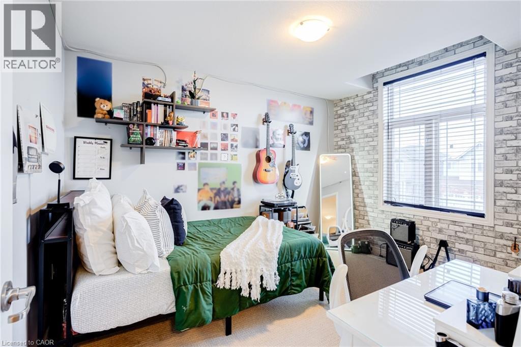 Bedroom featuring a large window with blinds, a white brick-patterned accent wall, and built-in wall shelving - 7 Kinsman Drive, Binbrook, ON - Indoor