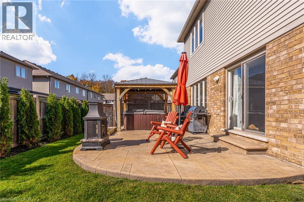 Outdoor stamped concrete patio featuring a gazebo, hot tub, and exterior fireplace - 7 Kinsman Drive, Binbrook, ON - Outdoor With Deck Patio Veranda