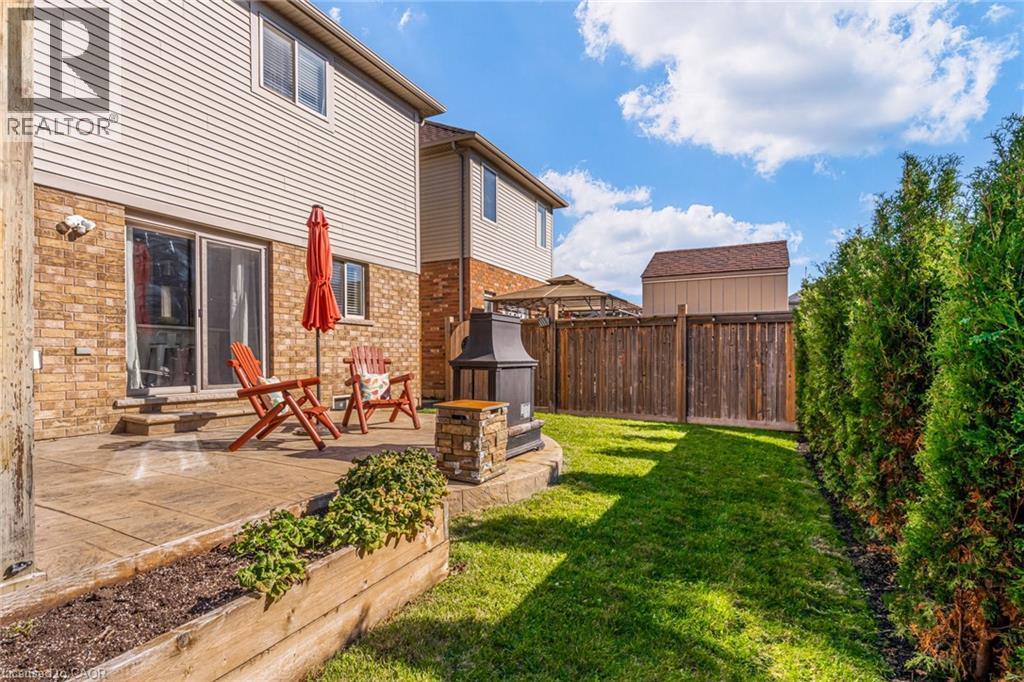Rear yard featuring a stamped concrete patio, sliding glass door access, and a built-in stone fire pit - 7 Kinsman Drive, Binbrook, ON - Outdoor With Deck Patio Veranda