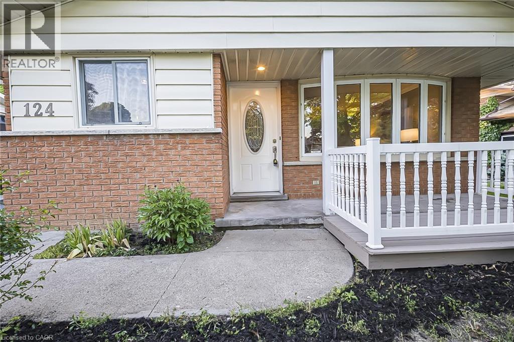 Brick facade with light-colored siding, a covered front porch featuring white railings, and a curved concrete walkway - 124 Dunsmere Drive, Kitchener, ON - Outdoor With Deck Patio Veranda