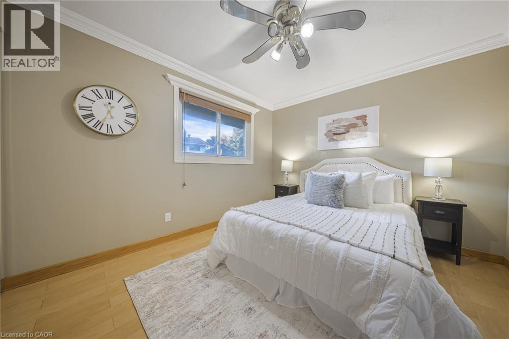 Bedroom featuring light wood-finish flooring, crown molding, a ceiling fan with integrated lighting, and a window with blinds - 124 Dunsmere Drive, Kitchener, ON - Indoor Photo Showing Bedroom