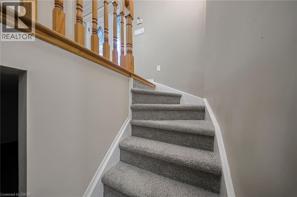 Carpeted staircase with light gray walls, white trim, and a wood-finish handrail and balusters - 124 Dunsmere Drive, Kitchener, ON - Indoor Photo Showing Other Room