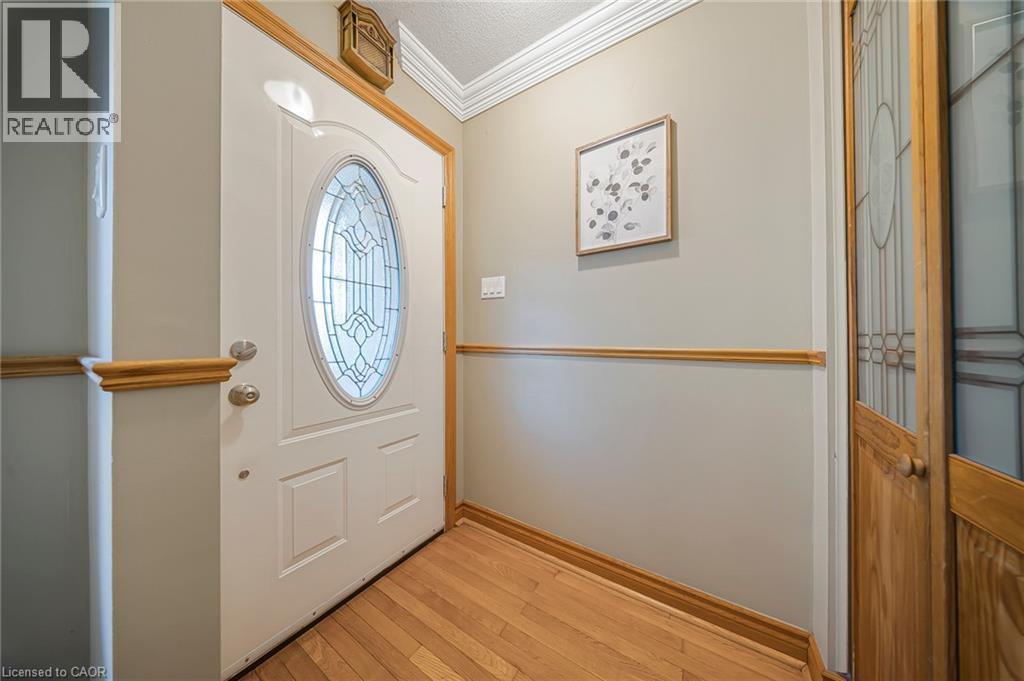 Entryway featuring a white door with decorative oval glass, wood-finish flooring, wood trim throughout, and crown molding - 124 Dunsmere Drive, Kitchener, ON - Indoor Photo Showing Other Room