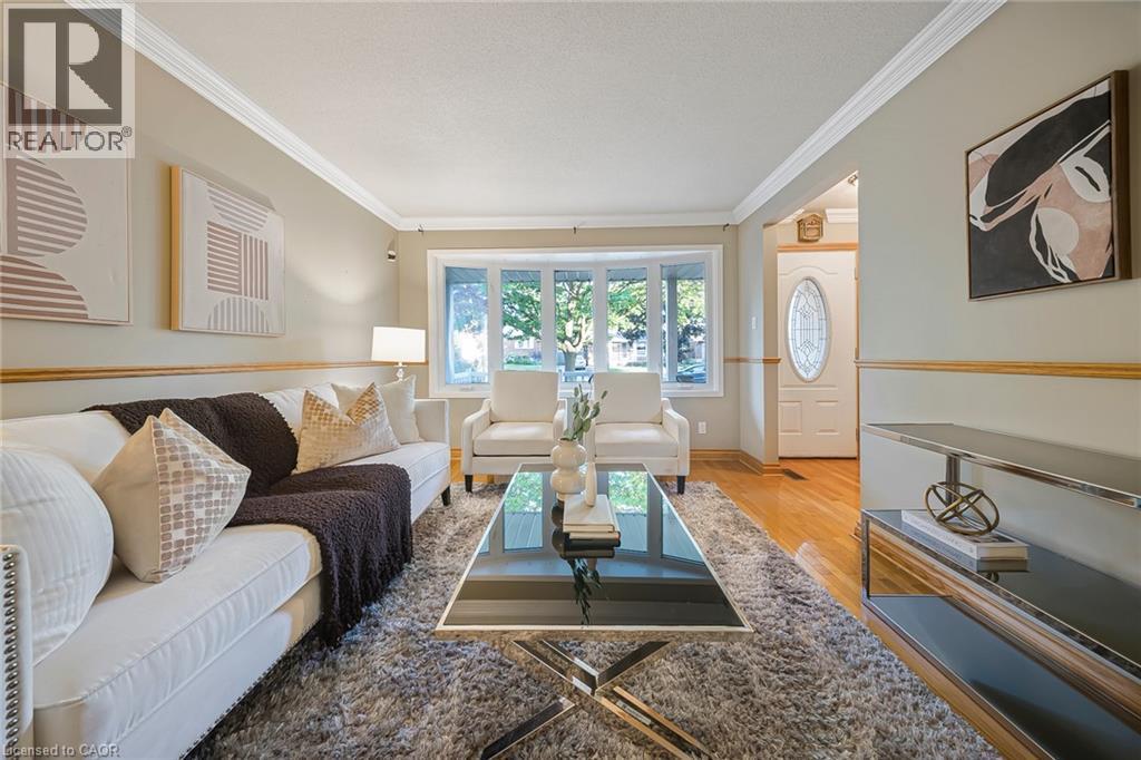 Living area featuring hardwood flooring, crown molding, and a front entry door with an oval glass insert - 124 Dunsmere Drive, Kitchener, ON - Indoor Photo Showing Living Room