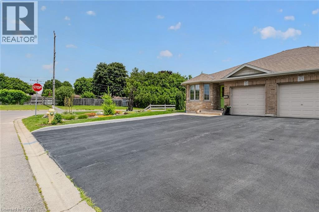 Brick facade residence featuring two attached garage doors, a bay window, and a light green entry door - 51 Millcroft Drive, Simcoe, ON - Outdoor