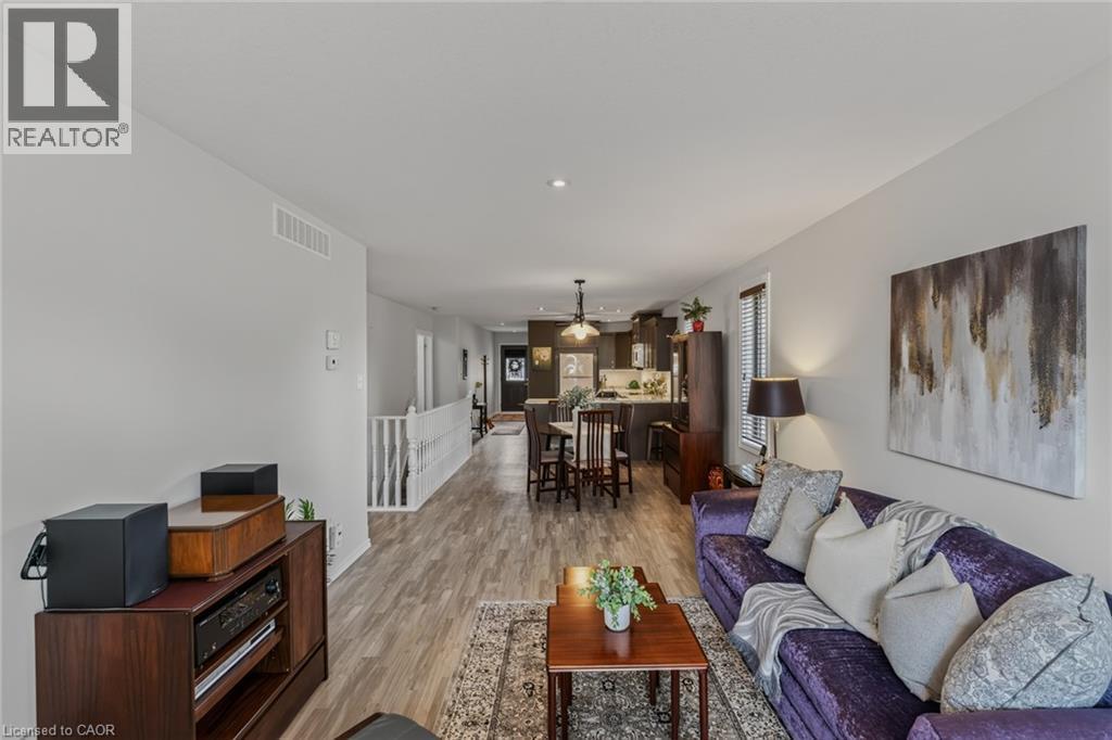 Open-concept living area featuring wood-finish flooring, recessed lighting, a white painted railing, and a window with horizontal blinds - 51 Millcroft Drive, Simcoe, ON - Indoor Photo Showing Living Room
