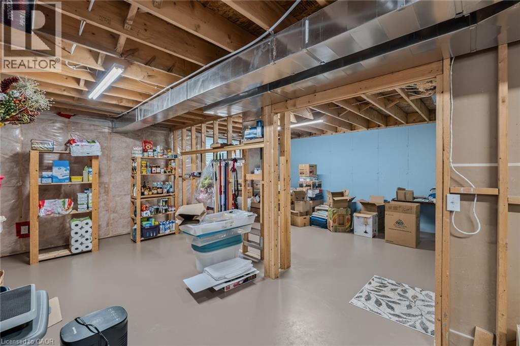 Unfinished basement space featuring exposed wooden joists, concrete flooring, fluorescent lighting, and partially framed walls - 51 Millcroft Drive, Simcoe, ON - Indoor Photo Showing Basement
