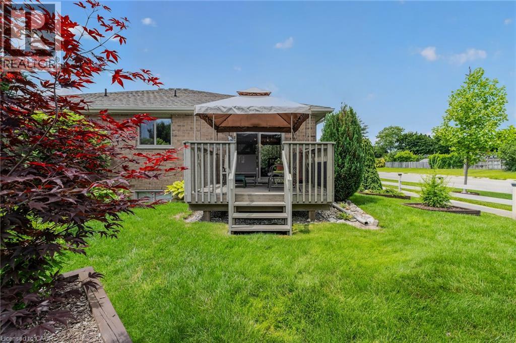 Rear wood deck with stairs to lawn, featuring a gazebo and sliding glass door entry to the brick-sided residence - 51 Millcroft Drive, Simcoe, ON - Outdoor
