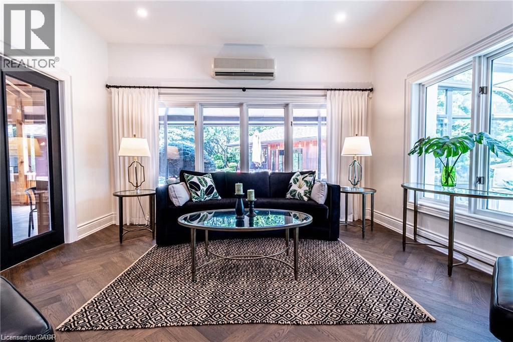 Bright interior space featuring large windows, wood-finish herringbone flooring, a black-framed glass panel door, and recessed lighting - 76 Adriatic Boulevard, Hamilton, ON - Indoor