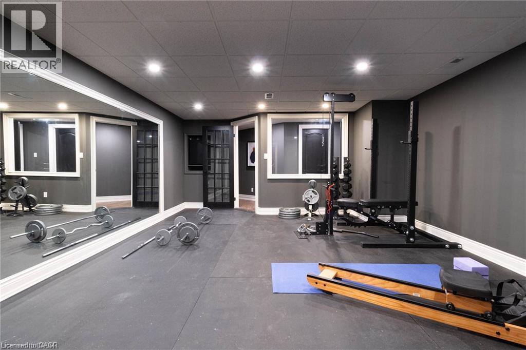 Dedicated fitness room featuring rubber flooring, recessed lighting, expansive wall mirror, and dual French-style doors - 76 Adriatic Boulevard, Hamilton, ON - Indoor Photo Showing Gym Room