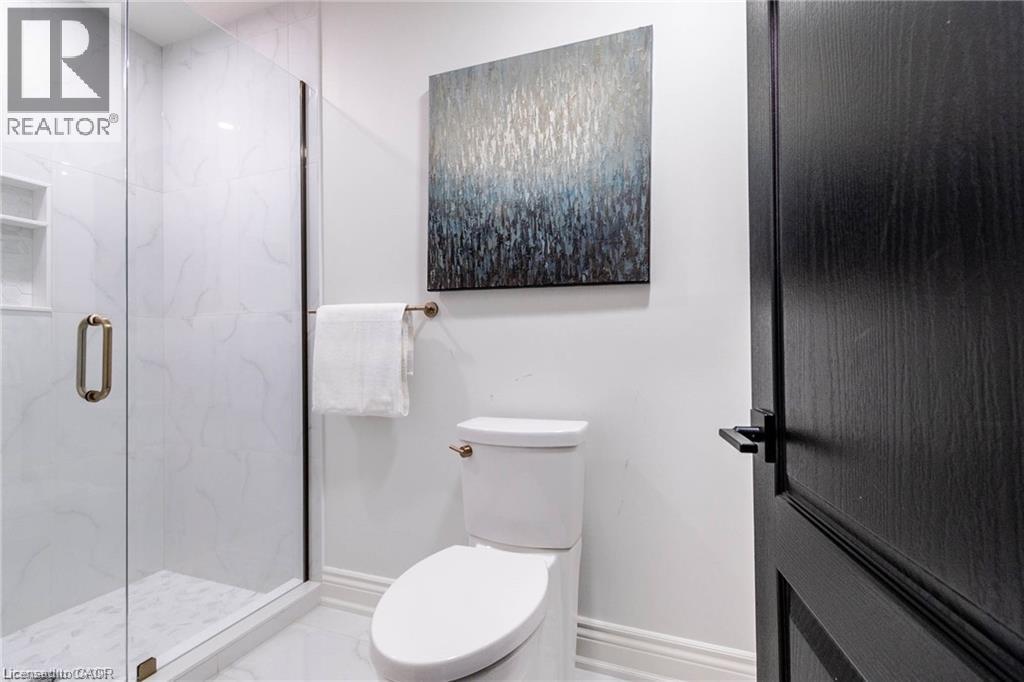 Shower featuring glass enclosure with bronze-finish hardware, built-in tiled niche, and white tile surround - 76 Adriatic Boulevard, Hamilton, ON - Indoor Photo Showing Bathroom