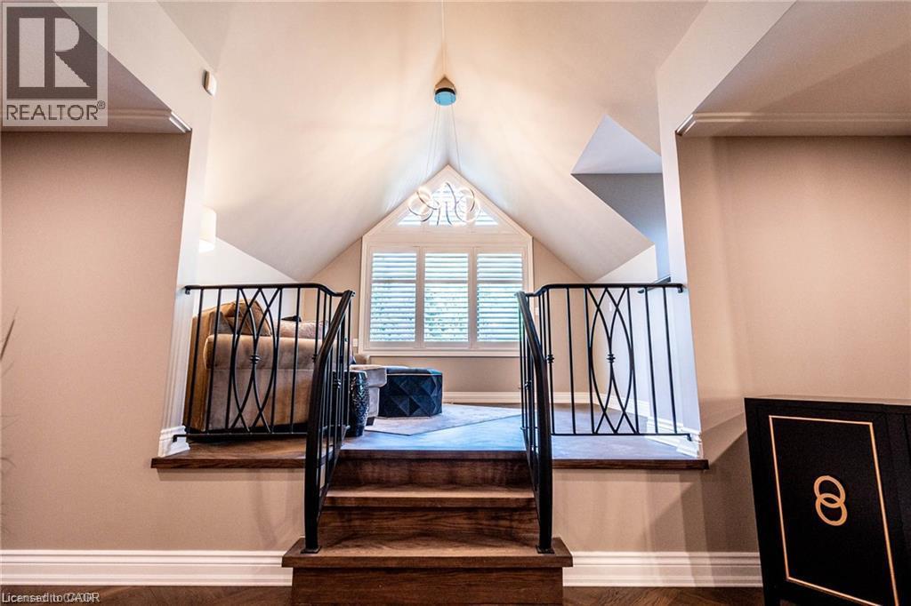 Raised platform area featuring wood-finish flooring, black wrought iron railings with oval detailing, and a prominent gable window with white plantation shutters - 76 Adriatic Boulevard, Hamilton, ON - Indoor Photo Showing Other Room