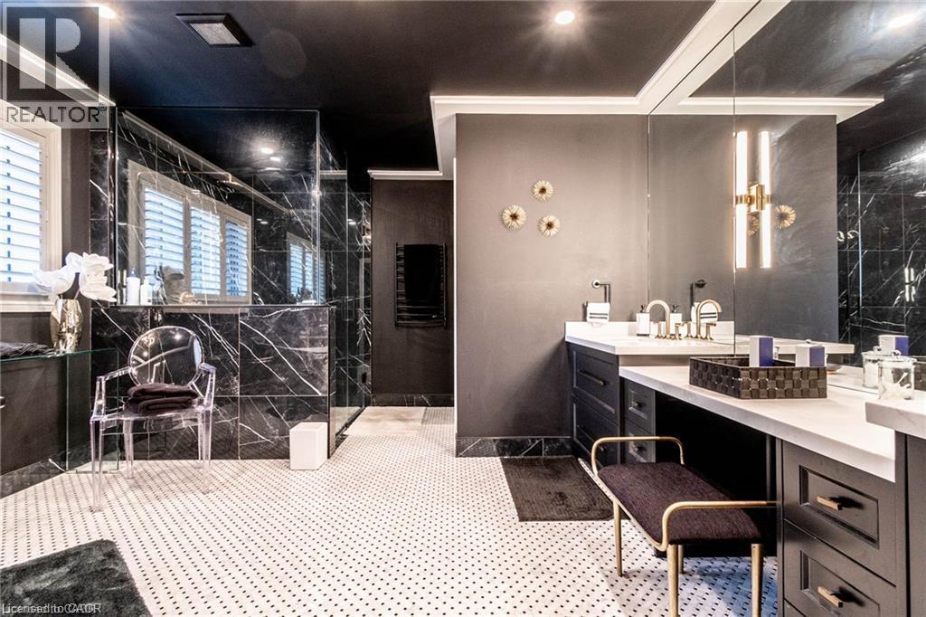 Bathroom featuring black marble-look wall tiling, a custom vanity with dual sinks, white countertop, and a built-in shower with glass enclosure - 76 Adriatic Boulevard, Hamilton, ON - Indoor Photo Showing Bathroom