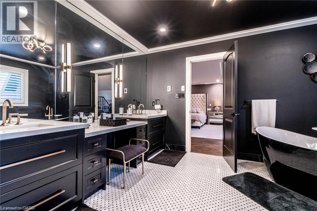 Modern bathroom featuring a freestanding black tub, dual vanities with white countertops, and contemporary wall-mounted lighting - 76 Adriatic Boulevard, Hamilton, ON - Indoor Photo Showing Bathroom