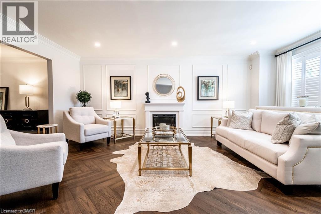 Herringbone wood-finish flooring complements a formal living space featuring a fireplace with a classic mantel - 76 Adriatic Boulevard, Hamilton, ON - Indoor Photo Showing Living Room With Fireplace