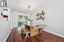 Dining area with rich wood-finish flooring, a contemporary chandelier, and sliding glass doors opening to an outdoor deck -