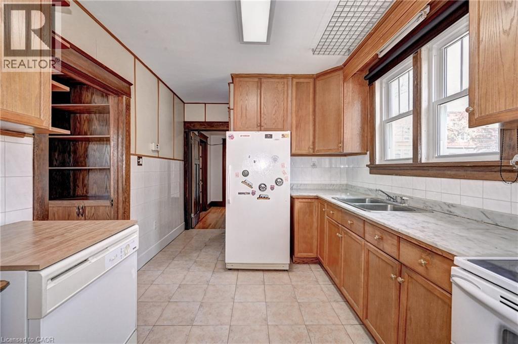Kitchen featuring wood cabinetry, a dual basin sink, and tile flooring - 147 Courtland Avenue E, Kitchener, ON - Indoor Photo Showing Kitchen With Double Sink