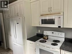 Kitchen featuring white cabinetry, dark speckled countertops, and an electric range with an over-the-range microwave -
