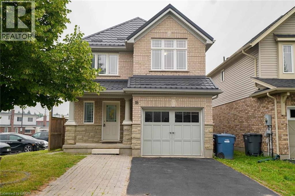 Two-story brick and stone facade residence featuring a covered front porch with white columns, a dark shingle roof, and a two-car garage with divided light windows - 18 Heritage Drive, Guelph, ON - Outdoor With Facade