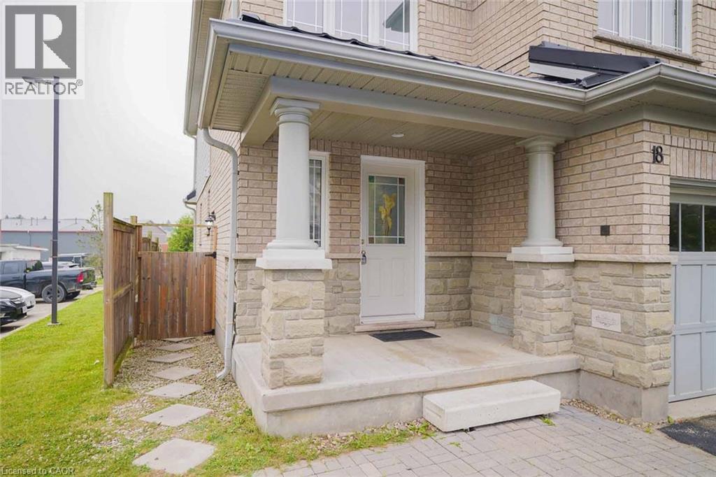 Front entry featuring a covered porch with stone-clad columns, a main door with decorative glass, and brick and stone veneer exterior - 18 Heritage Drive, Guelph, ON - Outdoor
