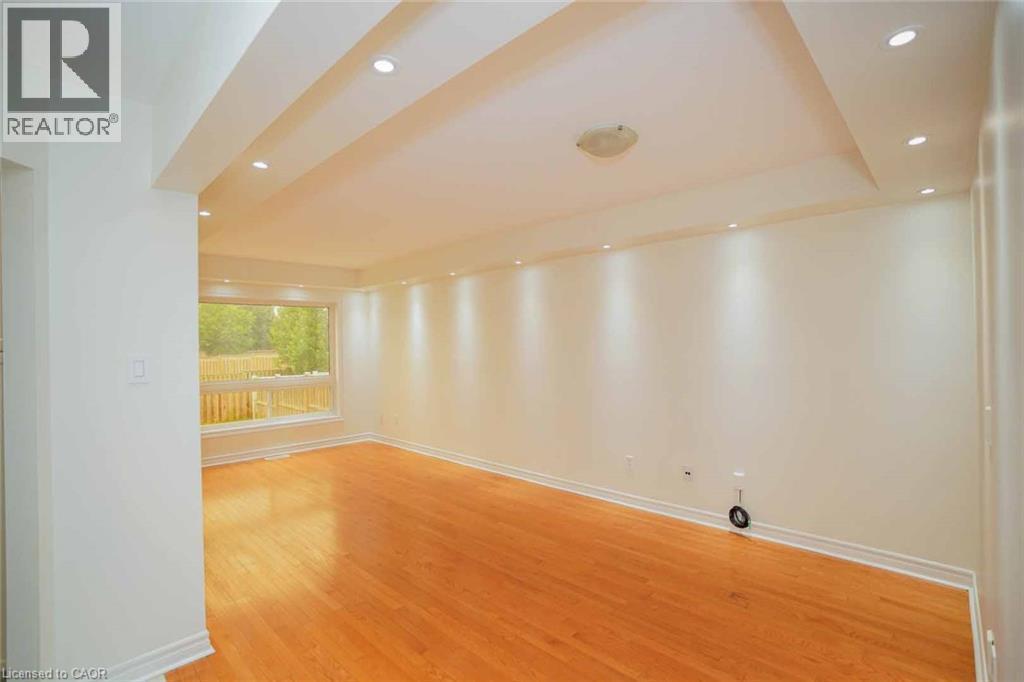 Spacious room featuring wood-finish flooring, recessed ceiling lighting, a large window, and light-toned wall finishes - 18 Heritage Drive, Guelph, ON - Indoor Photo Showing Other Room