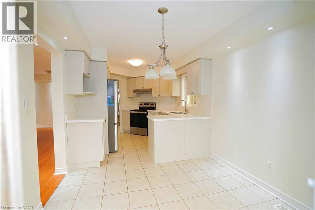 Bright kitchen and dining area featuring white cabinetry, stainless steel appliances, a double basin sink, and recessed lighting - 18 Heritage Drive, Guelph, ON - Indoor Photo Showing Kitchen