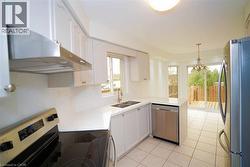Kitchen featuring white cabinetry, light-toned countertops, tile flooring, and stainless steel appliances -