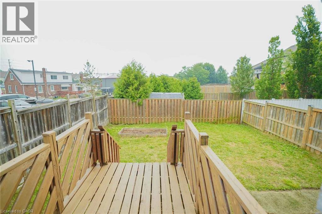 Deck with natural wood railing overlooking a fenced backyard with a raised garden bed - 18 Heritage Drive, Guelph, ON - Outdoor With Deck Patio Veranda