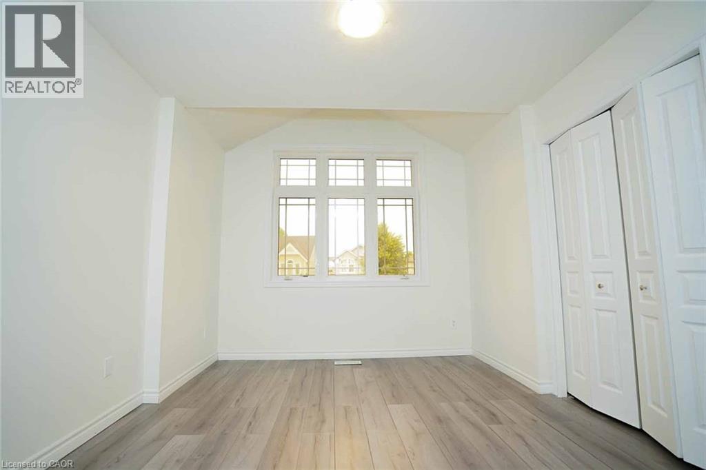 Room featuring wood-finish flooring, a multi-pane window, white walls, and bi-fold closet doors - 18 Heritage Drive, Guelph, ON - Indoor Photo Showing Other Room