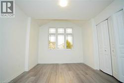 Room featuring wood-finish flooring, a multi-pane window, white walls, and bi-fold closet doors -