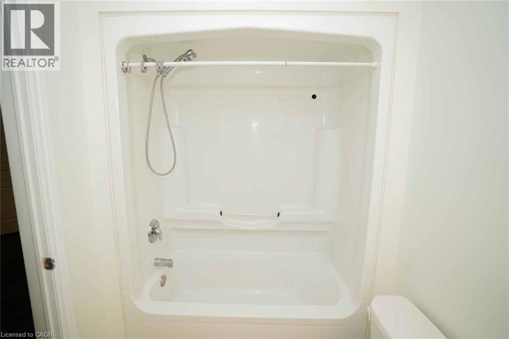 White fiberglass tub and shower combination with chrome fixtures, an integrated soap dish, and a handheld shower head - 18 Heritage Drive, Guelph, ON - Indoor Photo Showing Bathroom