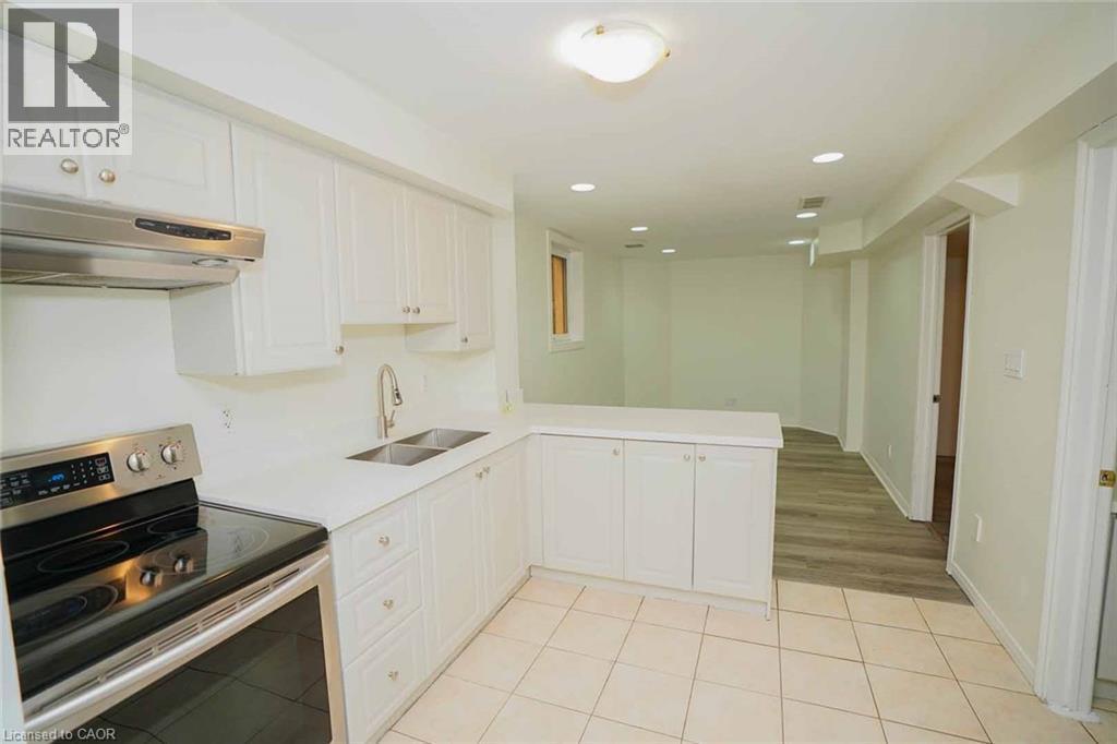 Contemporary kitchen featuring white cabinetry, stainless steel appliances, a double basin sink, and a peninsula with countertop seating - 18 Heritage Drive, Guelph, ON - Indoor Photo Showing Kitchen With Double Sink