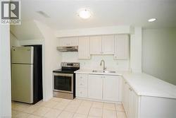 Kitchen featuring white cabinetry, light-toned countertops, a stainless steel range with overhead ventilation, and a stainless steel refrigerator -