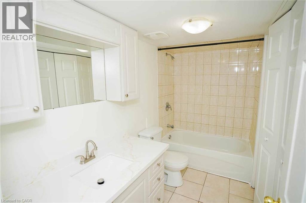 Bathroom featuring a white vanity with an integrated rectangular sink, brushed nickel faucet, and a stone-finish countertop - 18 Heritage Drive, Guelph, ON - Indoor Photo Showing Bathroom