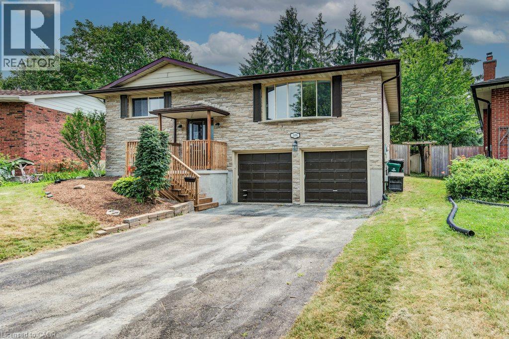 Stone facade residence featuring a covered front entrance with wood railings, a two-car garage, and mature landscaping - 109 White Oak Place, Waterloo, ON - Outdoor