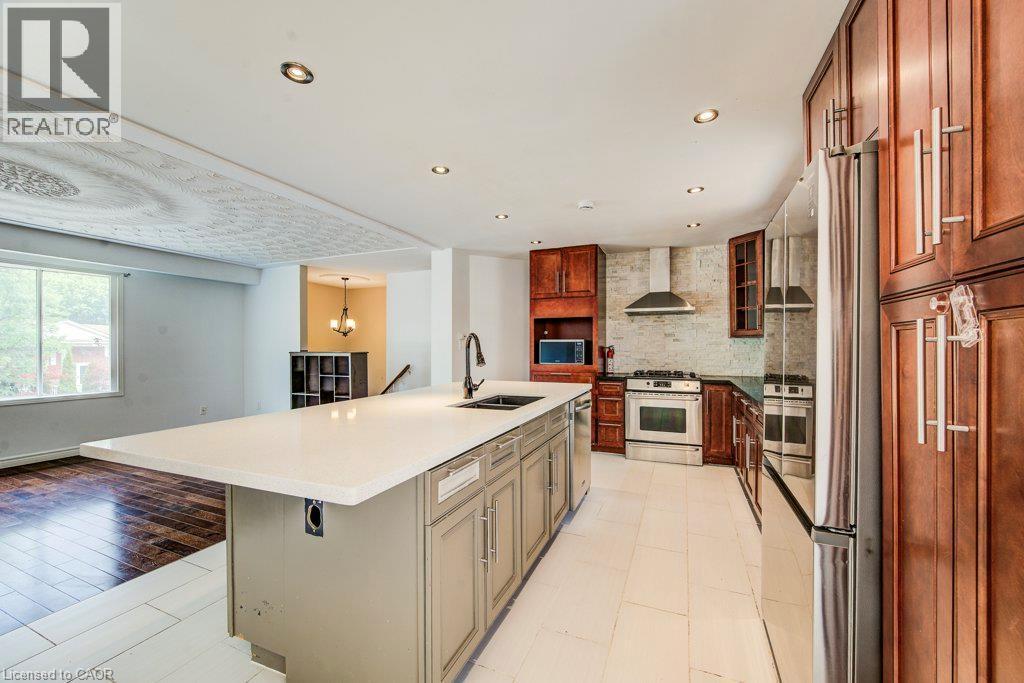 Kitchen featuring a central island with an integrated sink, stainless steel appliances, dark wood cabinetry, and recessed lighting - 109 White Oak Place, Waterloo, ON - Indoor Photo Showing Kitchen With Double Sink With Upgraded Kitchen