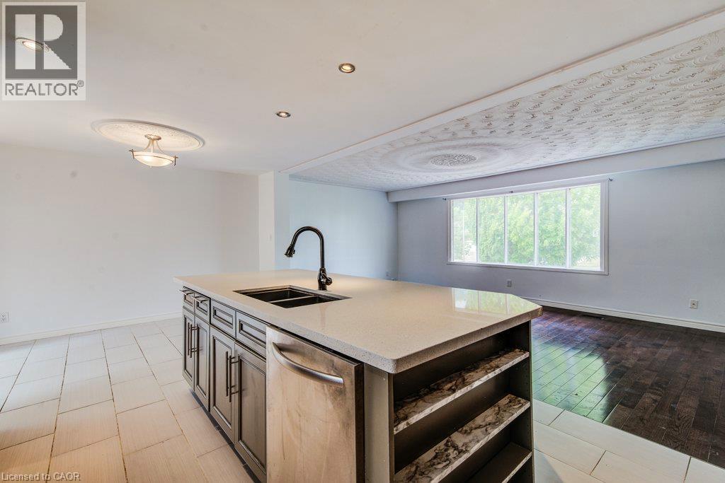 Kitchen island featuring a double basin sink with a matte black faucet, light-toned countertop, and integrated dishwasher - 109 White Oak Place, Waterloo, ON - Indoor Photo Showing Kitchen With Double Sink